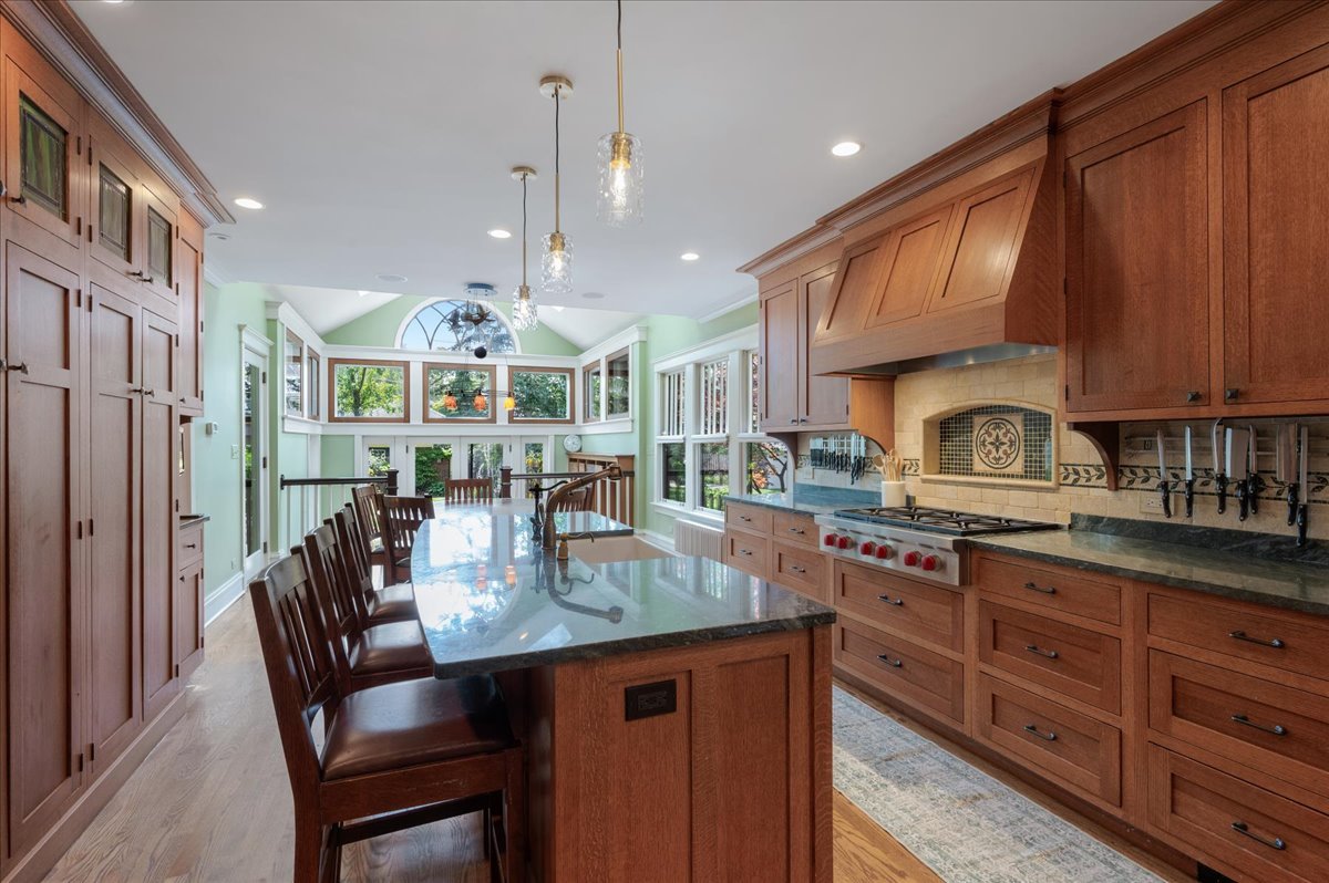 623 Forest Avenue Wilmette, IL 60091 - Photo 10 of 43 a kitchen with stainless steel appliances granite countertop a stove top oven a sink dishwasher a dining table and chairs with wooden floor