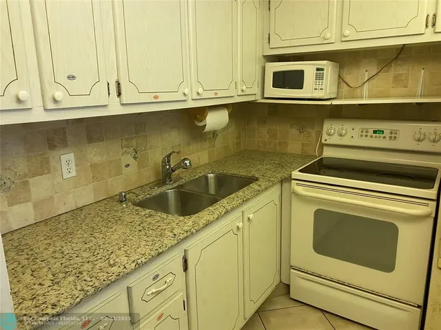 a kitchen with granite countertop a sink and stove top oven