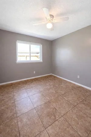 an empty room with windows and ceiling fan