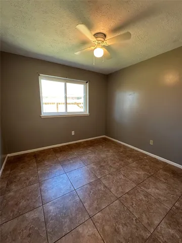 a view of an empty room and window and chandelier fan