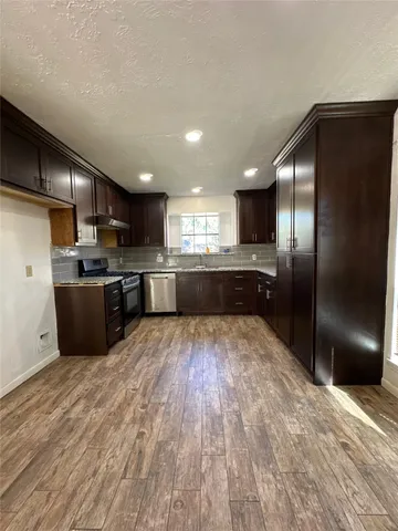 a large kitchen with kitchen island a large counter top stainless steel appliances and cabinets