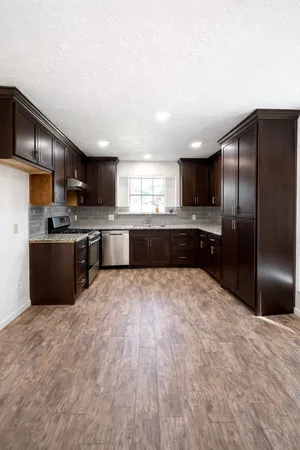a large kitchen with stainless steel appliances granite countertop a refrigerator and a stove top oven