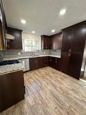 a large kitchen with granite countertop a sink and cabinets