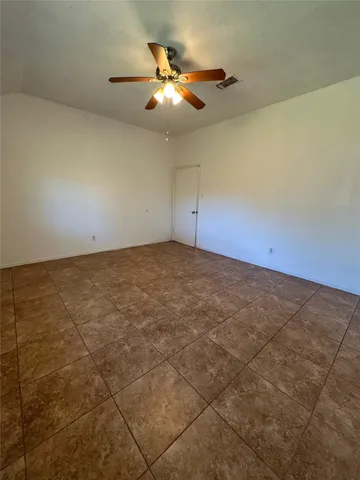 an empty room with a chandelier fan and windows