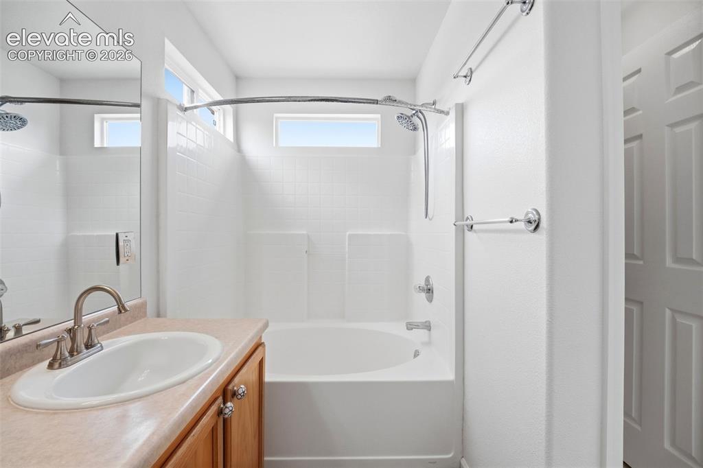 7904 Coffee Road Peyton, CO 80831 - Photo 25 of 48 Bathroom featuring a neutral-toned vanity with an integrated sink, polished chrome faucet, and wood-finish cabinetry