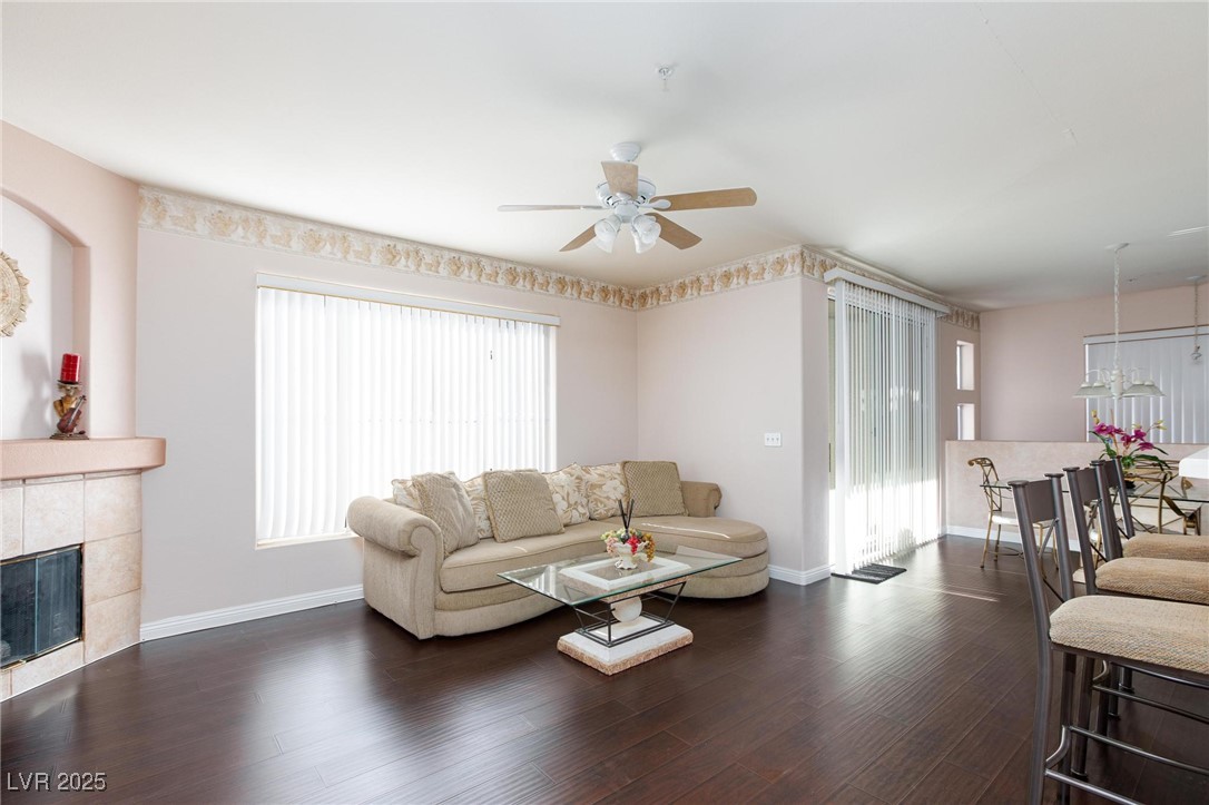 7185 South Durango Drive, Unit 201 Las Vegas, NV 89113 - Photo 8 of 27 Living room featuring dark wood finished floors, a tiled fireplace, and ceiling fan with light