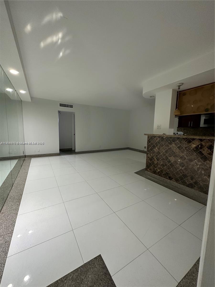 1100 Northeast 1st Court, Unit 105 Hallandale Beach, FL 33009 - Photo 11 of 13 a living room with a couch and a flat screen tv