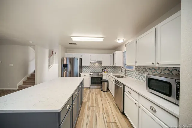 a large kitchen with a stove sink and cabinets