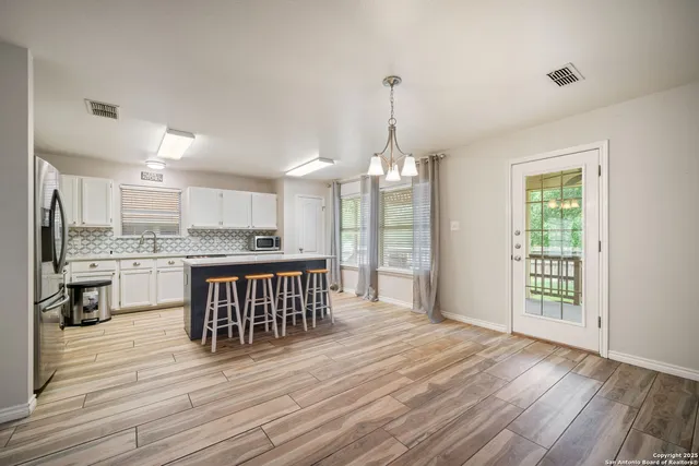 a open kitchen with granite countertop a stove refrigerator and a wooden floor