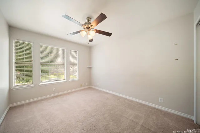 an empty room with windows and fan