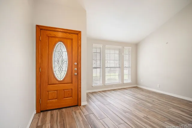 an empty room with wooden floor door and windows