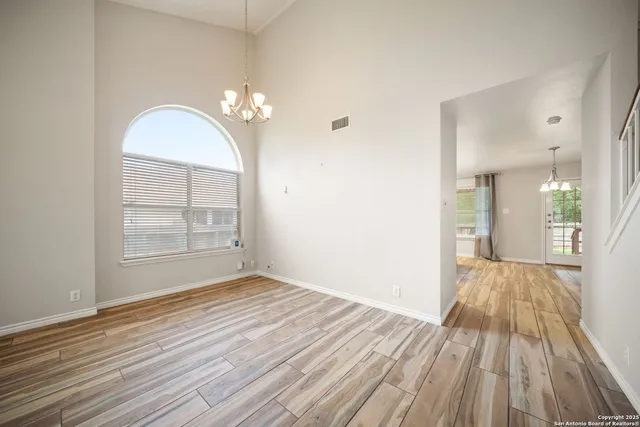an empty room with wooden floor cabinet and windows