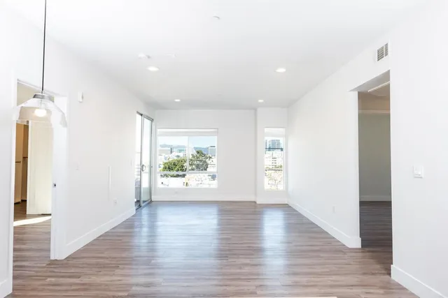 a view of an empty room with wooden floor and a window