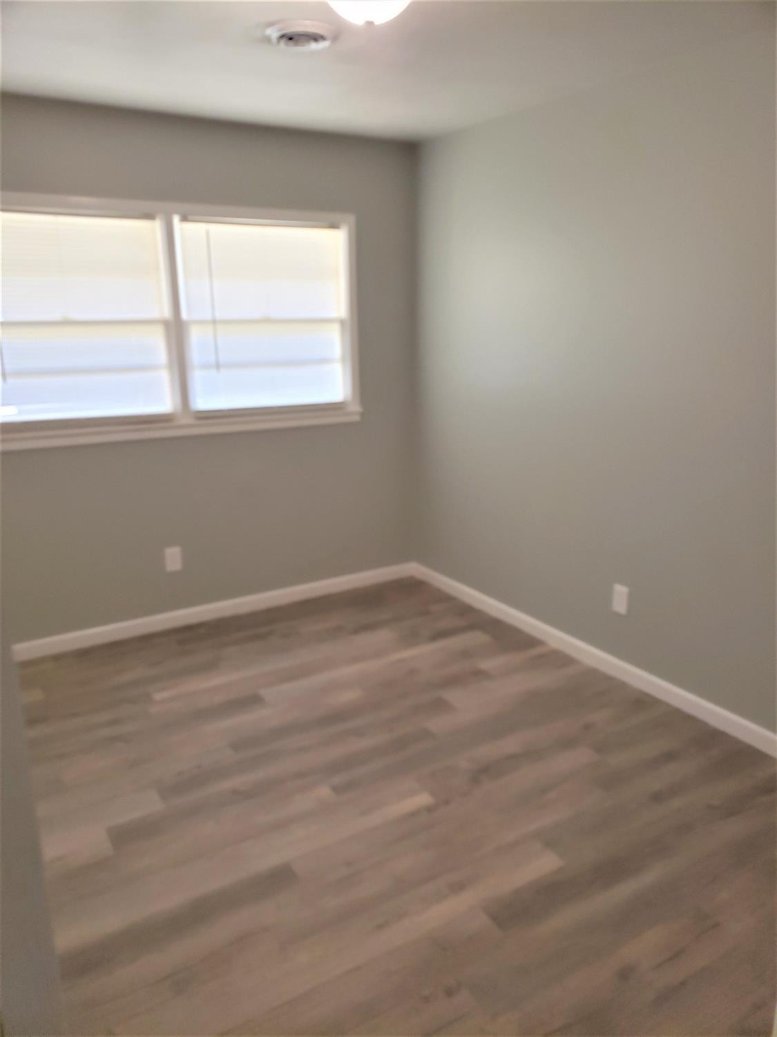4906 6th Street Lubbock, TX 79416 - Photo 8 of 24 a view of an empty room with wooden floor and a window