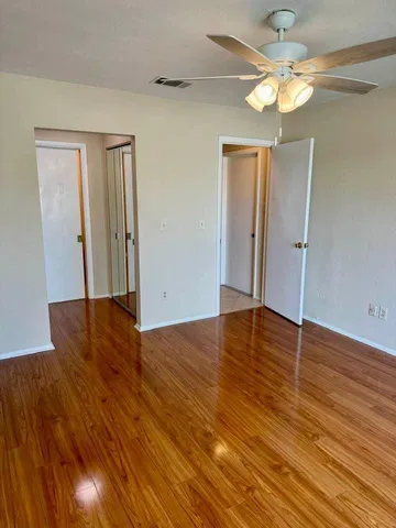 a view of empty room with wooden floor and fan