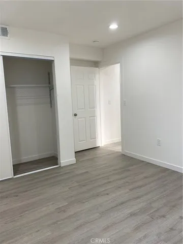 a view of an empty room with wooden floor & closet