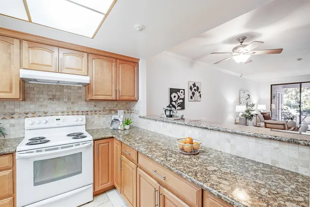 a kitchen with stainless steel appliances granite countertop a stove a sink and a granite counter tops with white cabinets