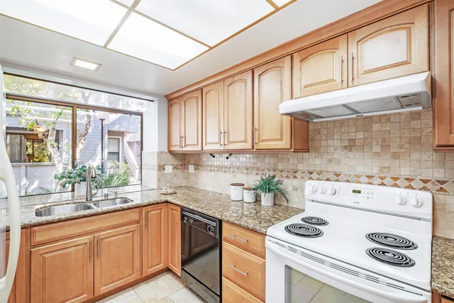 a kitchen with stainless steel appliances granite countertop a sink a stove and cabinets