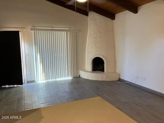 a view of an empty room with window and chandelier fan