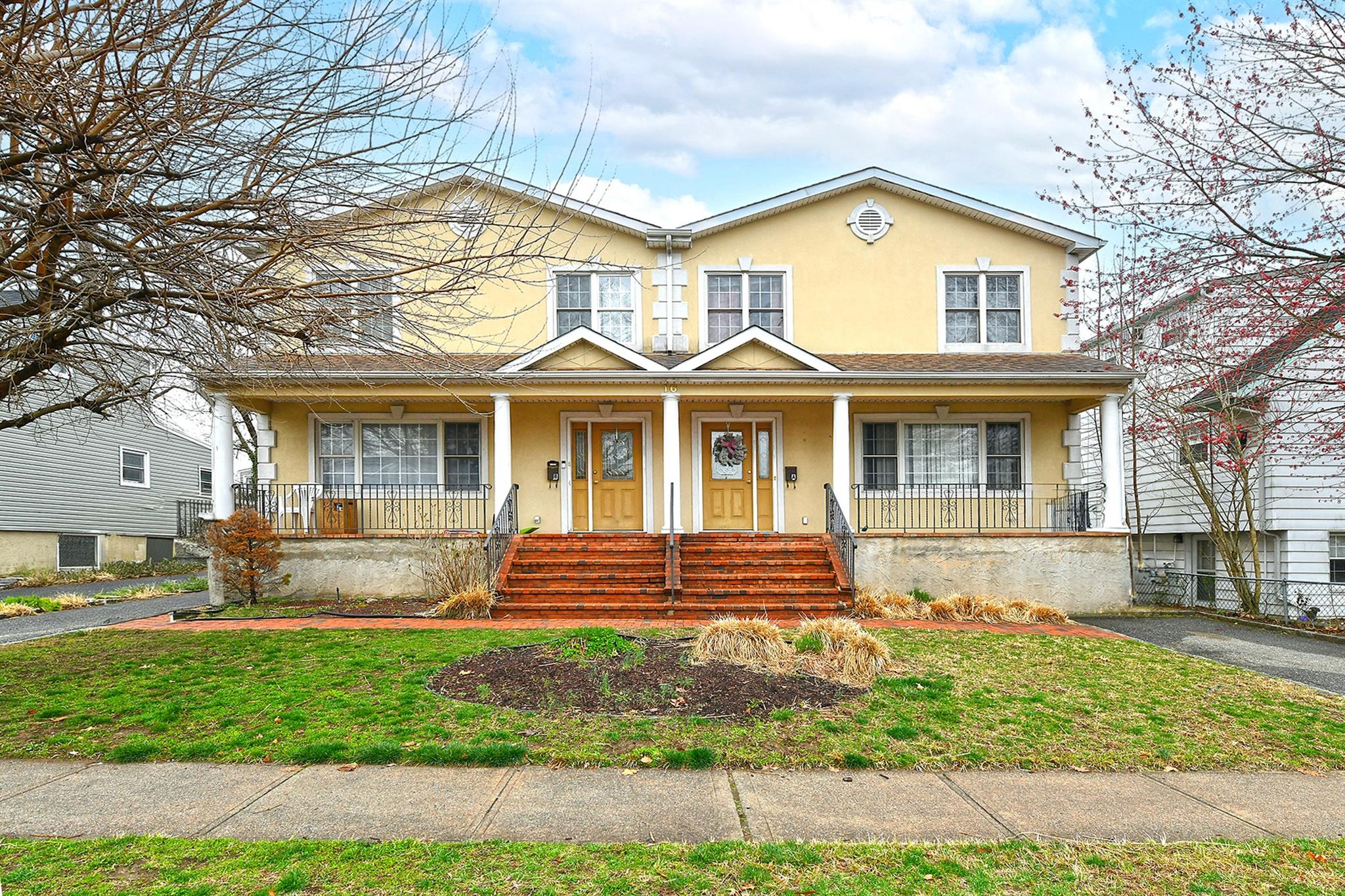 16 Inwood Road Port Washington, NY 11050 - Photo 1 of 1 View of front of house with a front yard, stucco siding, and covered porch