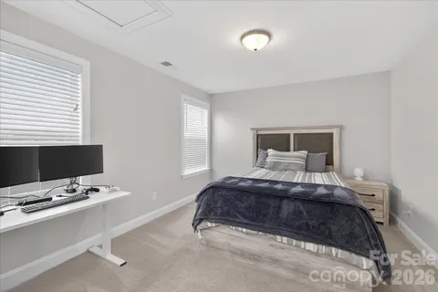 a bedroom with a bed computer on desk and a window