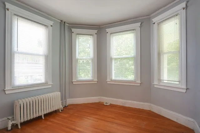 a view of an empty room with a window and wooden floor