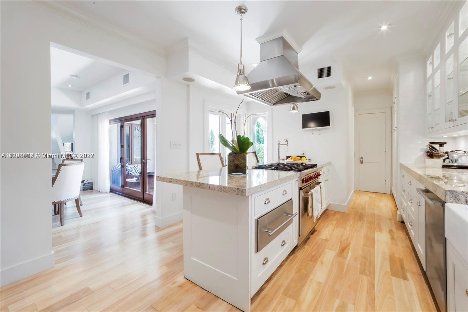 5768 Pine Tree Drive Miami Beach, FL 33140 - Photo 6 of 17 a large kitchen with stainless steel appliances a large counter top a sink a stove and a wooden floors