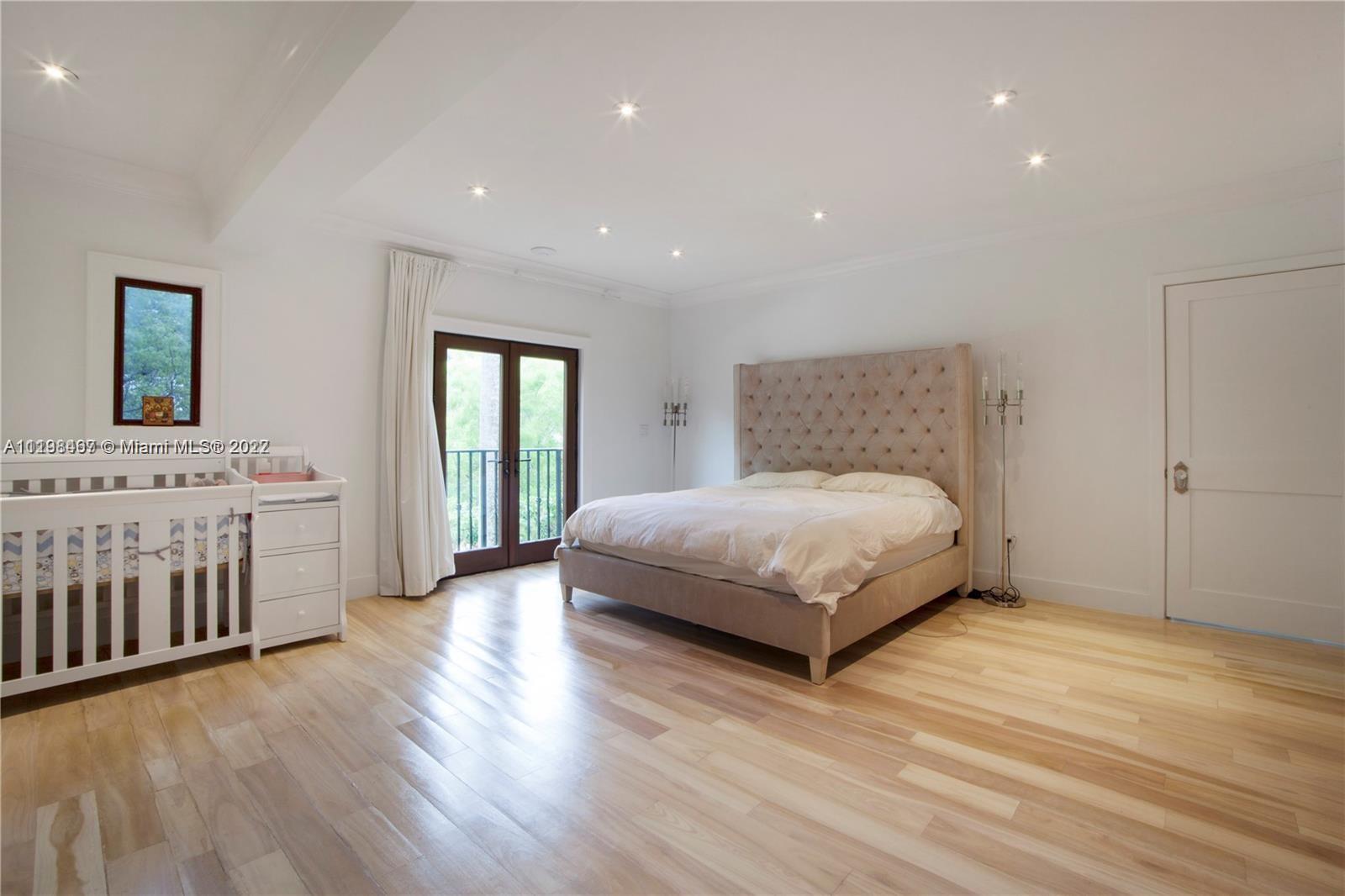 5768 Pine Tree Drive Miami Beach, FL 33140 - Photo 9 of 17 a bedroom with a large bed and a wooden floor