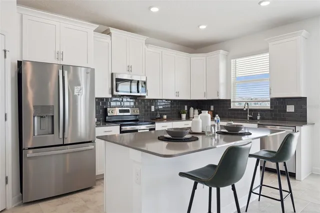 a kitchen with stainless steel appliances granite countertop a stove a refrigerator a sink a stove and white cabinets