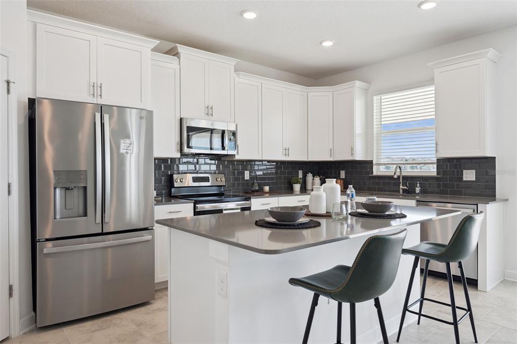 3012 Ella Way St. Cloud, FL 34771 - Photo 11 of 56 a kitchen with stainless steel appliances granite countertop a stove a refrigerator a sink a stove and white cabinets