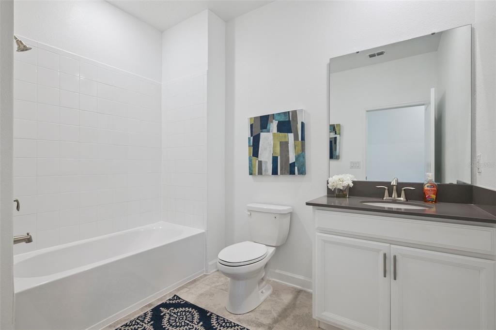 3012 Ella Way St. Cloud, FL 34771 - Photo 28 of 56 a bathroom with a granite countertop toilet a sink and a mirror