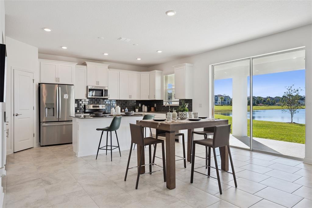 3012 Ella Way St. Cloud, FL 34771 - Photo 9 of 56 a kitchen with stainless steel appliances kitchen island granite countertop a table and chairs