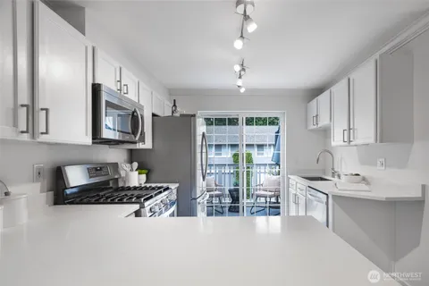 a kitchen with stainless steel appliances granite countertop a stove top oven a sink a dining table and chairs
