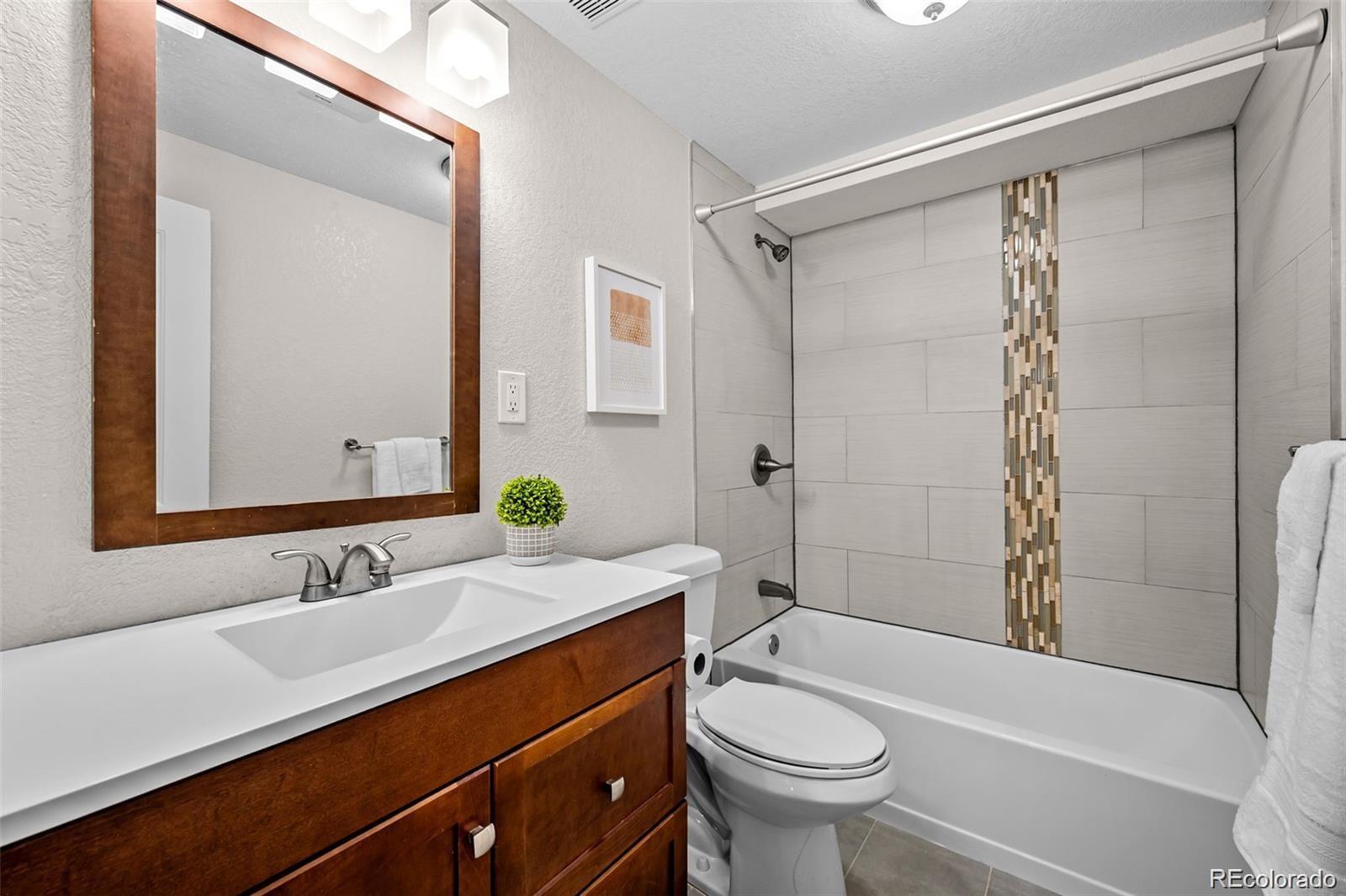 3649 Garfield Street Denver, CO 80205 - Photo 18 of 30 a bathroom with a sink a toilet a mirror a bathtub and shower