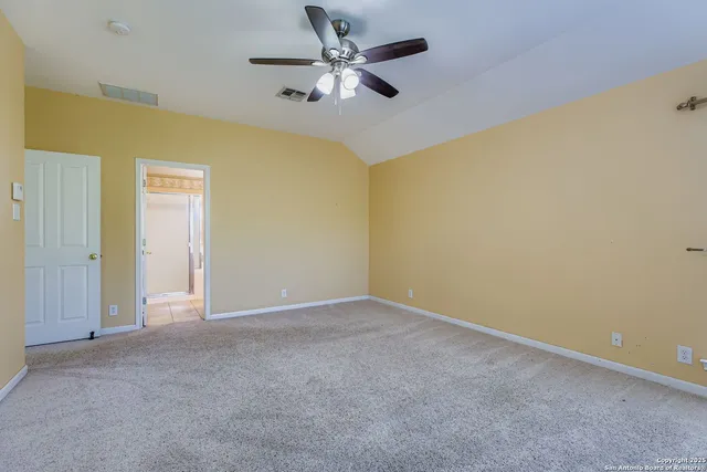 an empty room with a ceiling fan and carpet