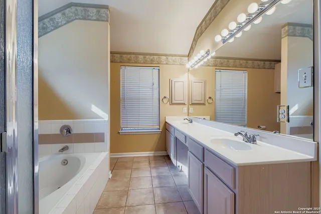 a bathroom with a bath tub a sink and a large mirror