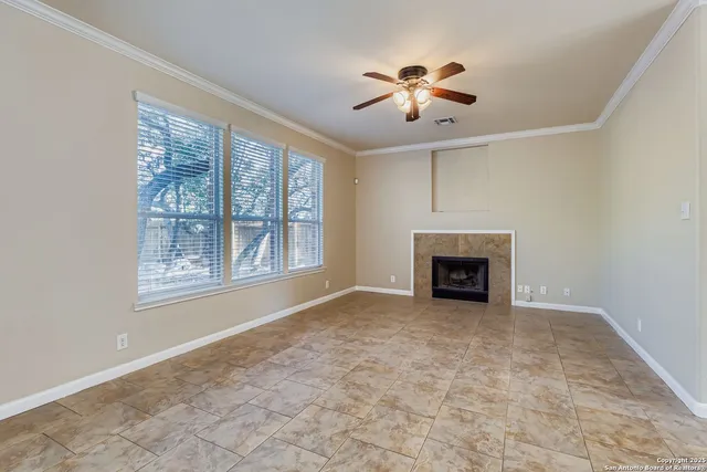 a view of an empty room with chandelier fan and fire place