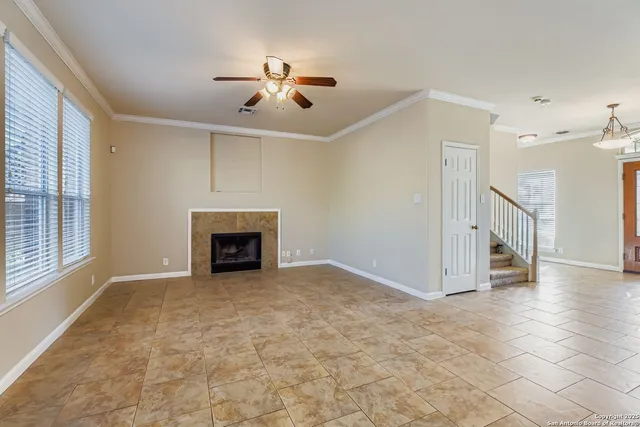 a view of an empty room with chandelier fan and fire place