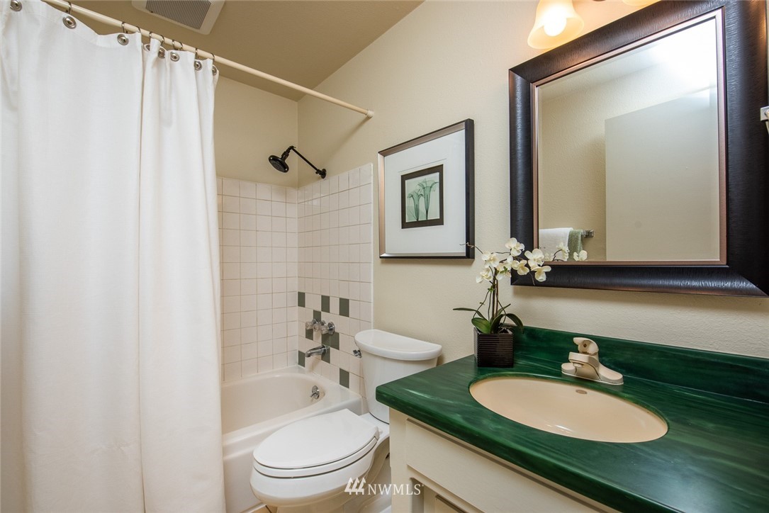 10044 Slater Avenue Northeast Kirkland, WA 98033 - Photo 15 of 21 a bathroom with a granite countertop sink toilet a mirror and shower