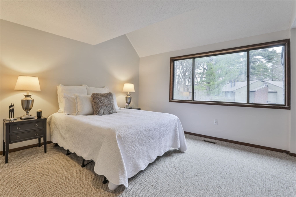 405 Great Elm Way, Unit 405 Acton, MA 01718 - Photo 16 of 19 a bedroom with a bed lamp and window