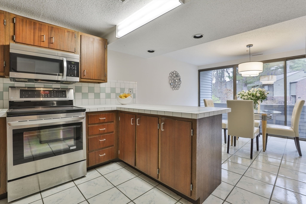 405 Great Elm Way, Unit 405 Acton, MA 01718 - Photo 8 of 19 a kitchen with stainless steel appliances a stove a sink and a microwave