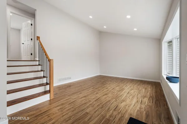 a view of an empty room with wooden floor and stairs