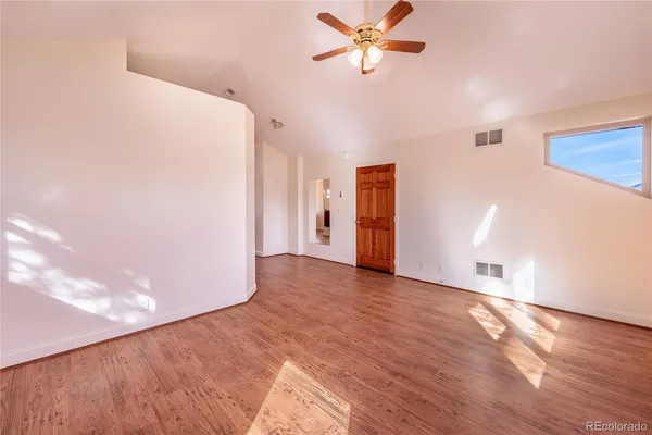 a view of a livingroom with wooden floor and a ceiling fan