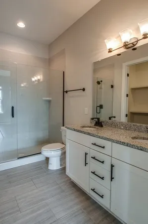 a bathroom with a granite countertop toilet a sink and a mirror