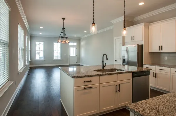 a kitchen with kitchen island granite countertop a sink cabinets and stainless steel appliances