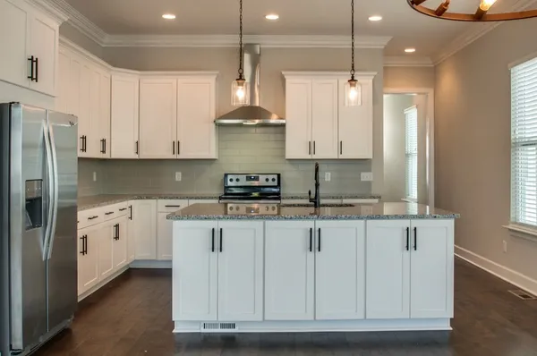 a kitchen with stainless steel appliances granite countertop a stove a sink and a refrigerator