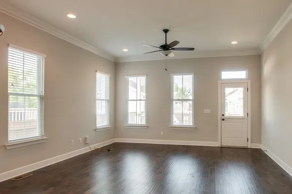 a view of an empty room with wooden floor and window