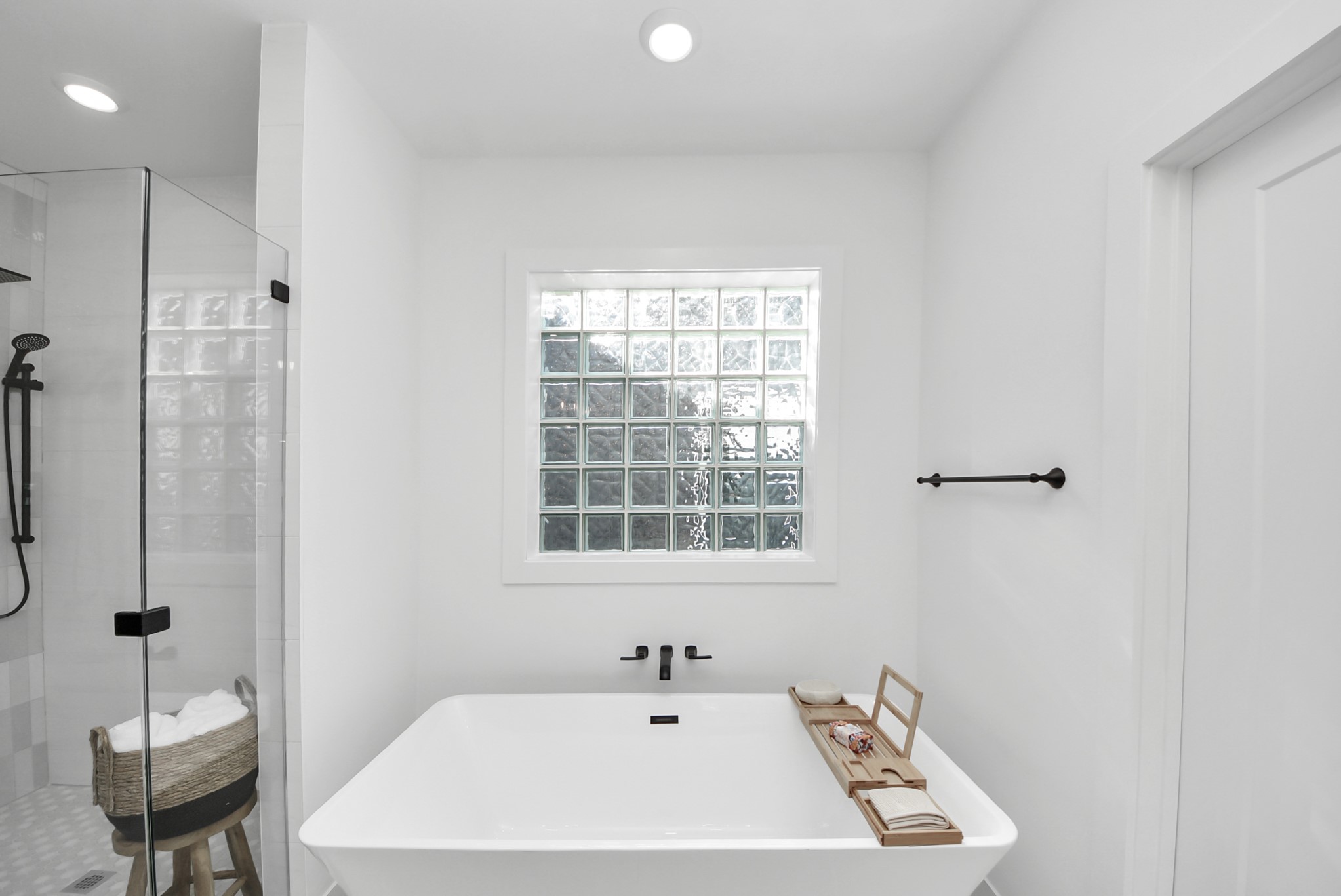 925 Fisher Street, Unit D Houston, TX 77018 - Photo 27 of 47 Relax in this minimalist bathroom, complete with a freestanding tub, glass-enclosed shower, and a large frosted window for natural light. Black fixtures contrast the clean white finishes, creating a modern, spa-like retreat.