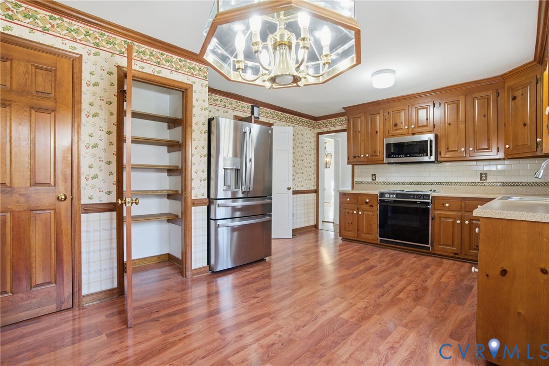 12918 Ashtree Road Midlothian, VA 23114 - Photo 12 of 43 a kitchen with stainless steel appliances granite countertop a stove top oven a refrigerator and a sink with wooden floor