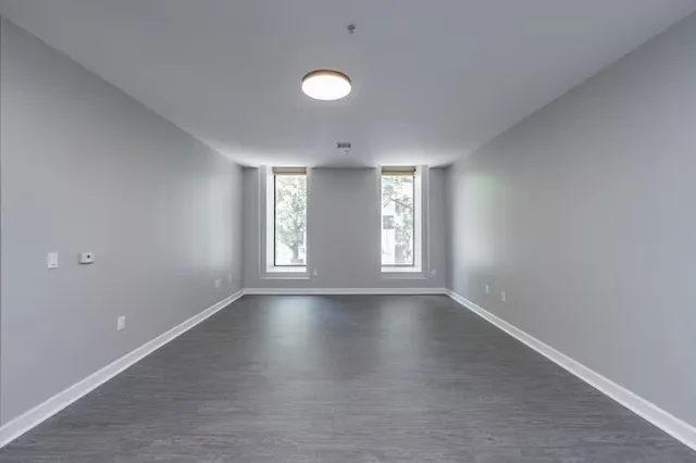 a view of an empty room with a window and wooden floor